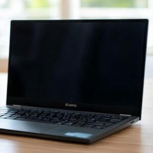 A CHUWI laptop with a black keyboard and screen sits on a wooden desk in a bright, naturally lit room.