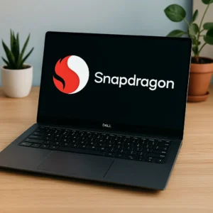 A digital photograph displays a modern Dell laptop with a Snapdragon logo on screen, sitting on a wooden desk with potted plants in the background.