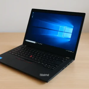 A photograph showcases a Lenovo ThinkPad laptop placed on a wooden desk with natural light highlighting its sleek design.