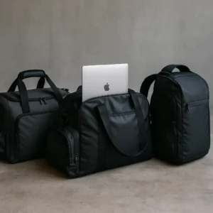 Duffel bags in a modern setting, each featuring dedicated laptop compartments, shoes stored separately, and gym accessories like towels and bottles placed nearby.