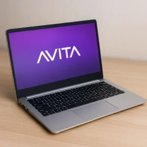 A silver AVITA laptop with a black chiclet keyboard displayed on a light wooden surface, showing the AVITA logo on its vibrant purple screen.
