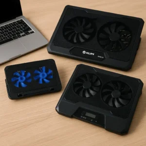 Three laptop cooling stands of different sizes placed on a wooden desk next to a silver laptop, showing black mesh surfaces and LED cooling fans.